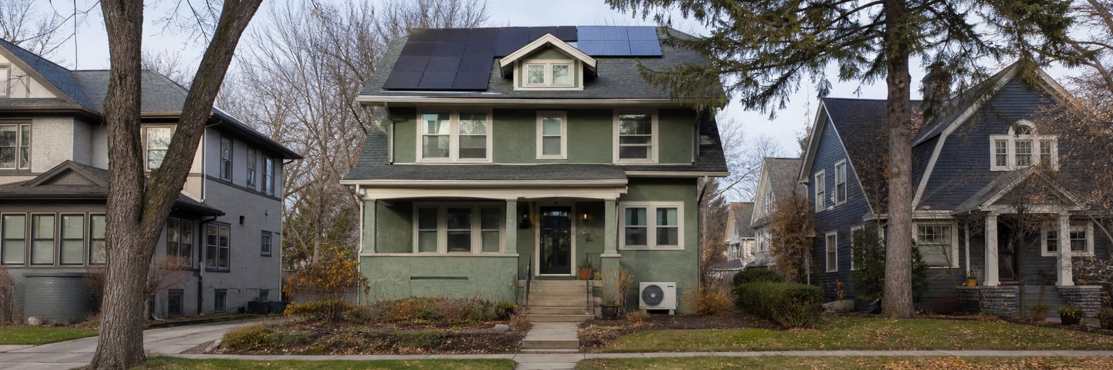 Representative older Minneapolis home with rooftop solar and a cold-climate heat pump