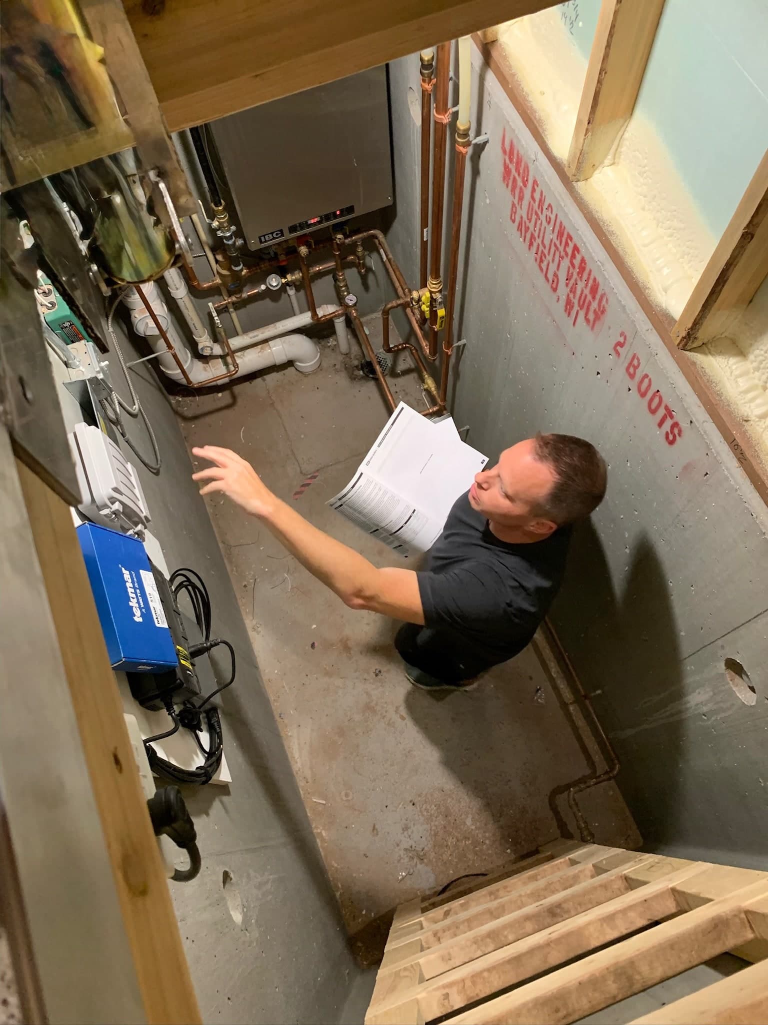 Nick Bender inspecting equipment in a residential mechanical room